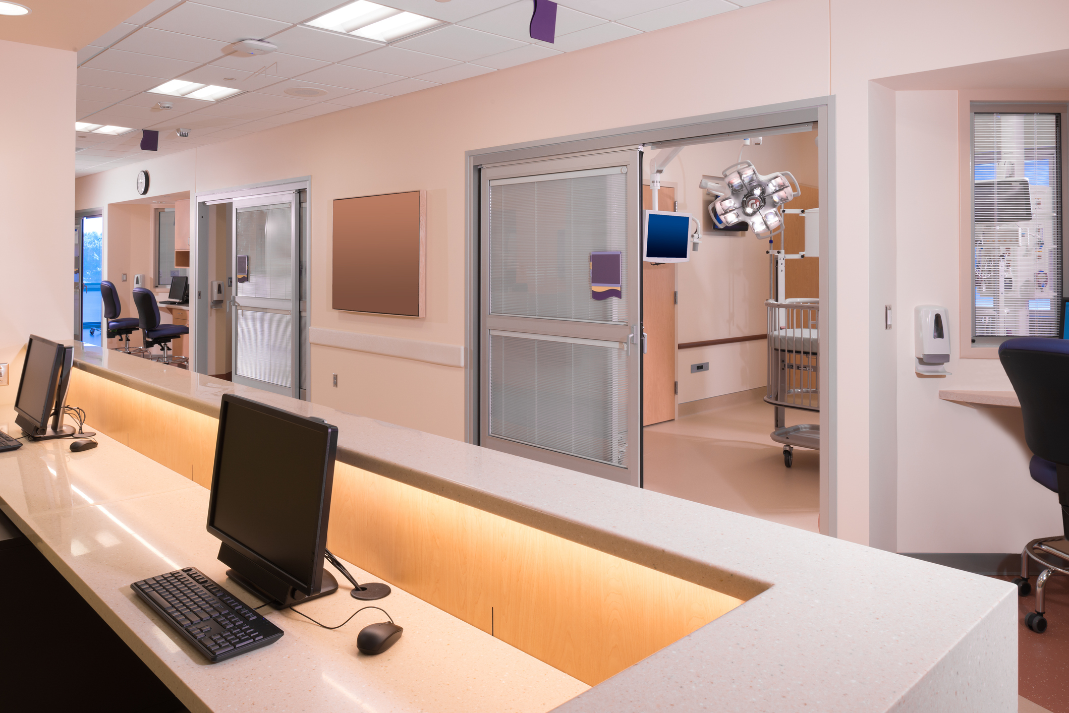 an empty hospital ward with computers and patient care rooms  