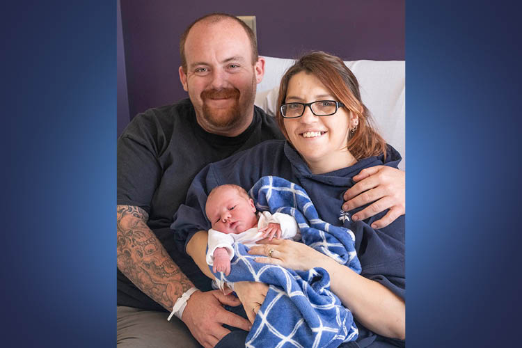 a man and woman hold their newborn in a hospital bed 