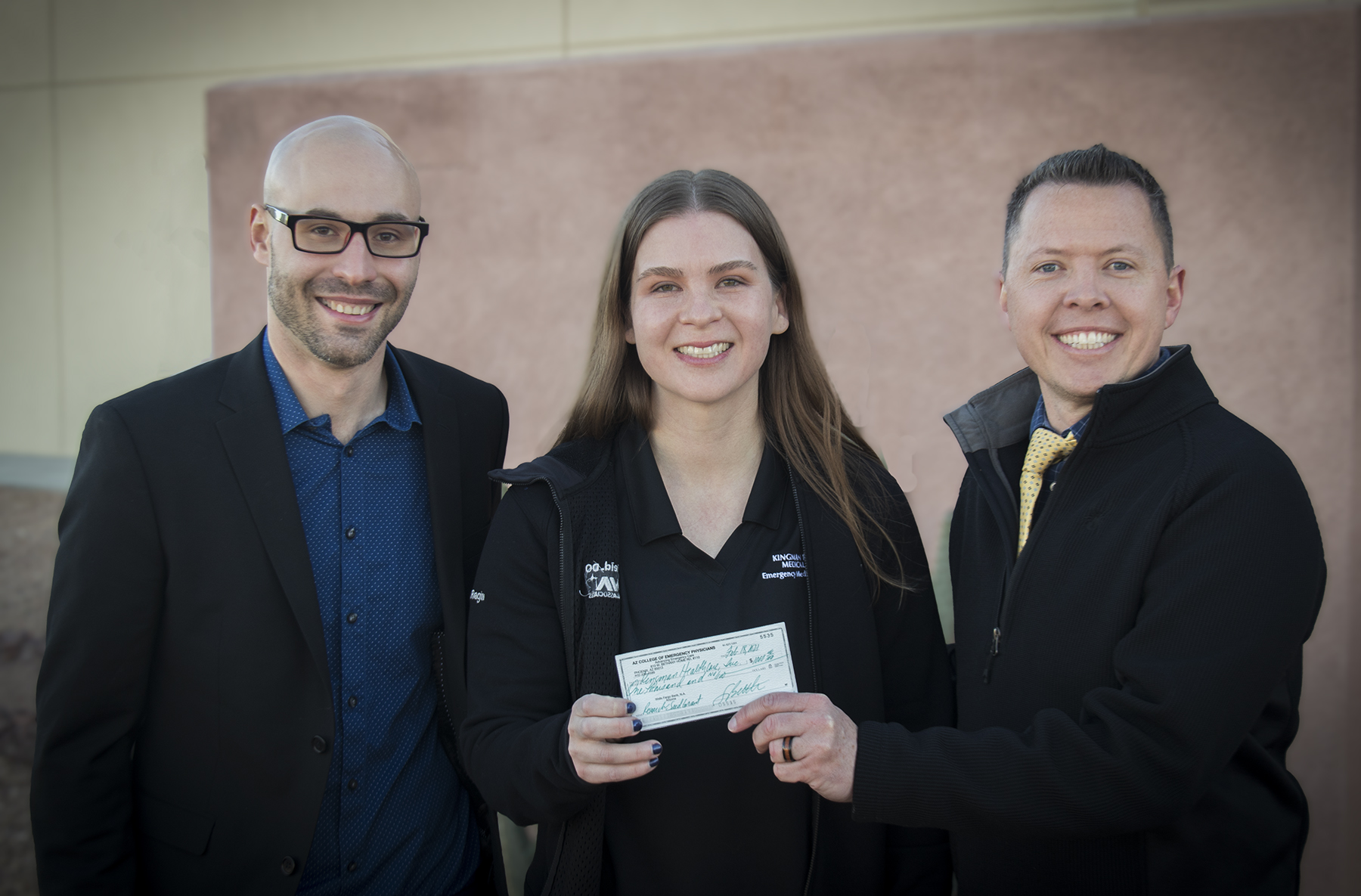 Drs. Santarelli, Reid, and Dawson smile while Dr. Reid holds a check in the middle