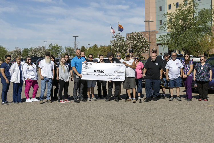 a large group of people stand in front of a hospital building with a large check