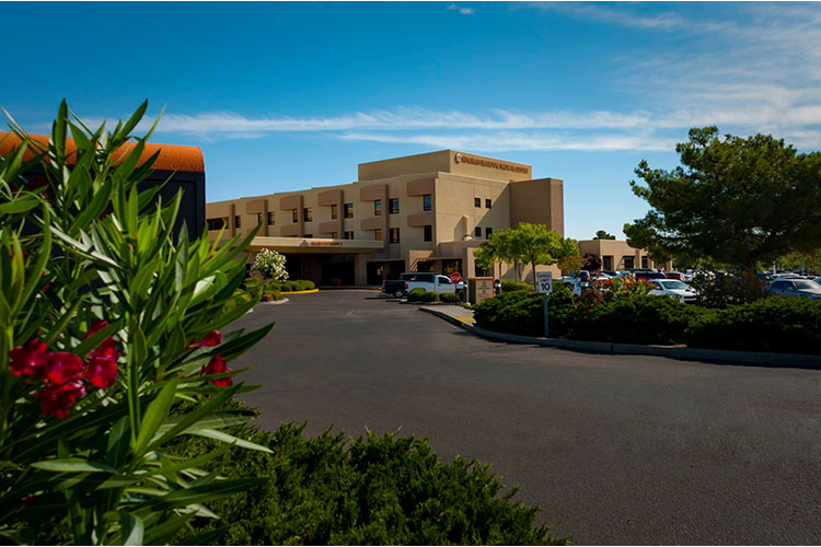 Kingman Regional Medical Center building framed in left foreground by blooming foliage