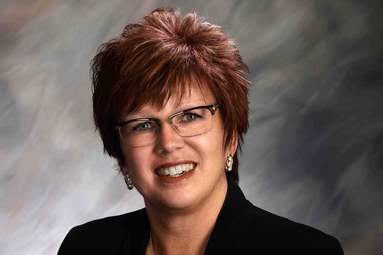 portait of Krystal Burge smiling before a gray, swirled background 