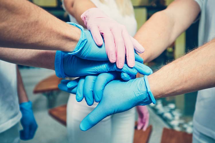 a group of people put their gloved hands together, focus is on the hands 