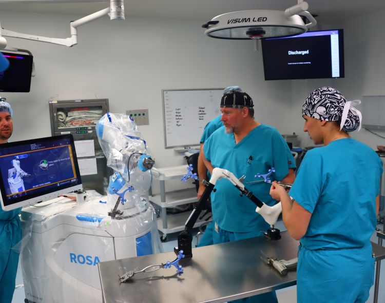 medical staff in scrubs look at a screen in an operating room during a mock knee replacement procedure