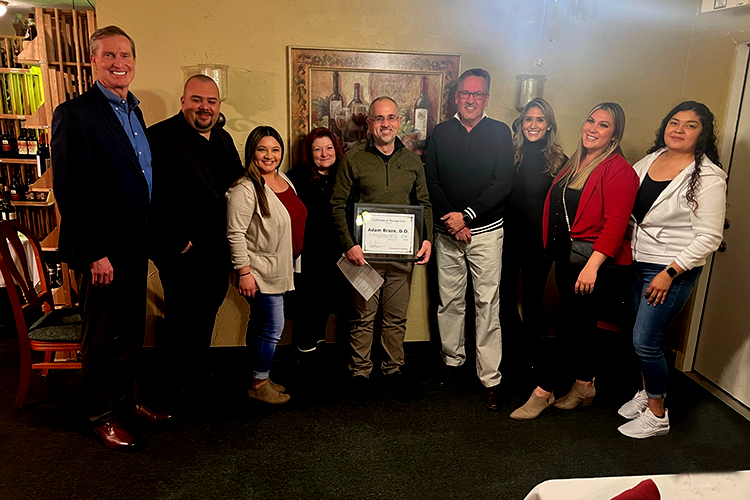 Dr. Adam Braze holds certificate in center surrounded by colleagues