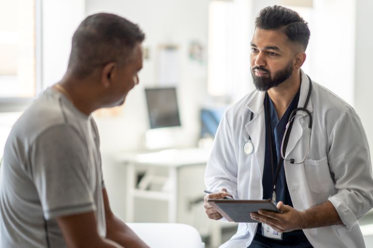 a provider with a clipboard talks to a patient who is shown in profile