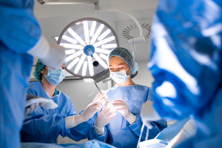 Medical team wears gloves and masks in a brightly lit room