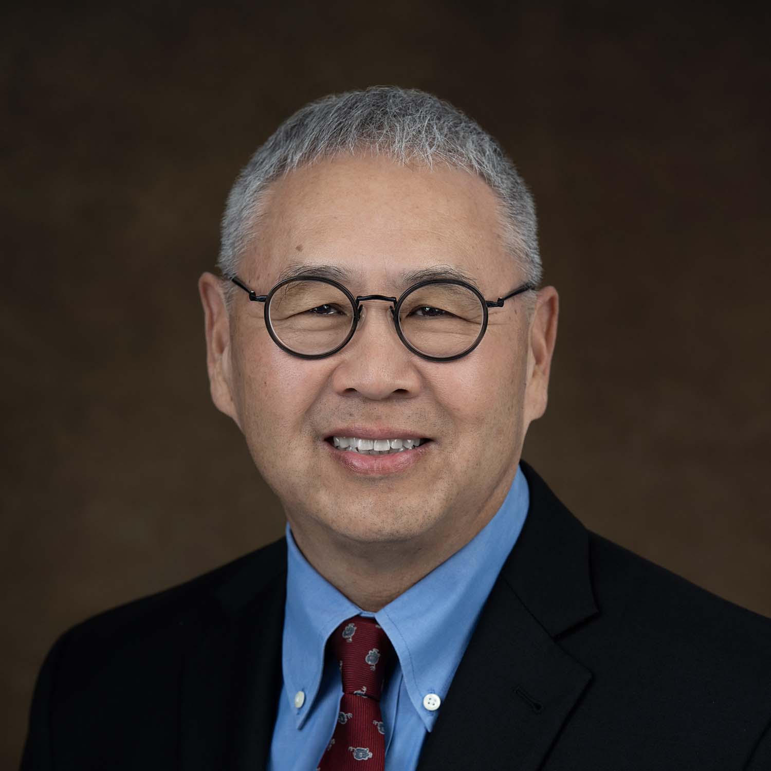 Dr. Craig Ono smiles before a brown backdrop