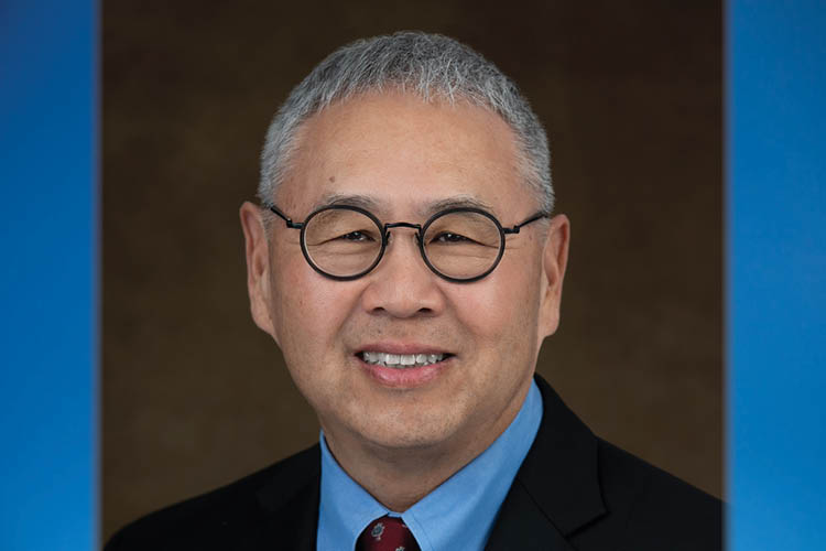 Dr. Craig Ono smiles before a brown backdrop