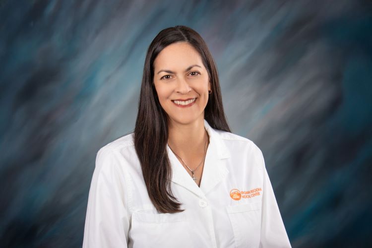 Dr. Schwartz smiles in a labcoat before a blue background