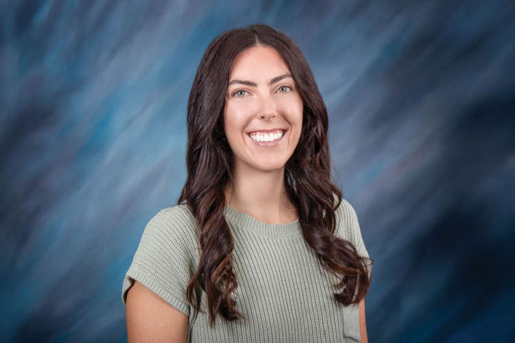 Maryssa Fairbanks, physician assistant, smiles before a blue background